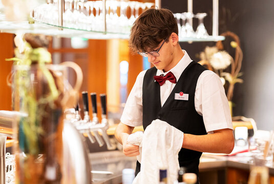 Servicekraft trocknet Glas an Bar