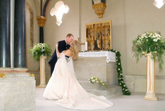 Hochzeitspaar küsst sich vor dem Altar in der Oberkapelle der Doppelkapelle Schloss Neuenburg