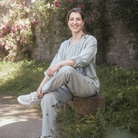 Nancy Weist strahlend und sitzend im Ganzkörperporträt