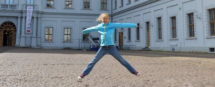 Kind hüpft freudig in die Höhe im Schlosshof von Schloss Neu-Augustusburg Weißenfels