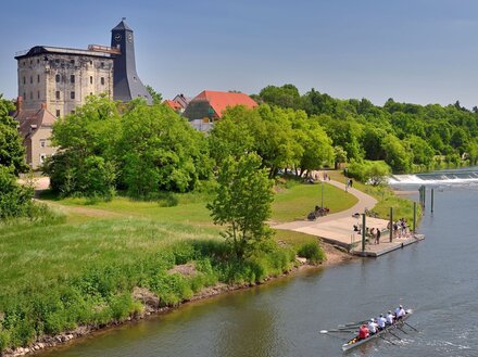 Wasserwanderer auf der Saale bei Bad Dürrenberg. Neben dem fluss ist eine große, grüne Wiese, links oben ist der Borlachturm zu sehen.