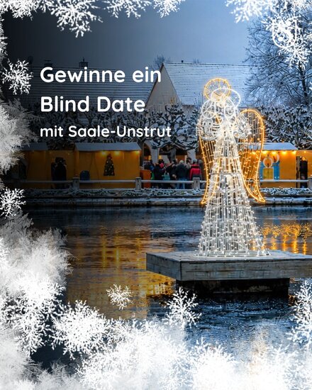 Engelsfigur aus Lichterketten wirft Reflektionen auf einen zugefrorenen Teich, drumherum Eiskristalle wie bei gefrorenen Fenstern und der Schriftzug "Gewinne ein Blind Date mit Saale-Unstrut§