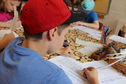 Junge übt das Schreiben mit Tinte und Feder wie im Mittelalter im Skriptorium des Klosters Memleben