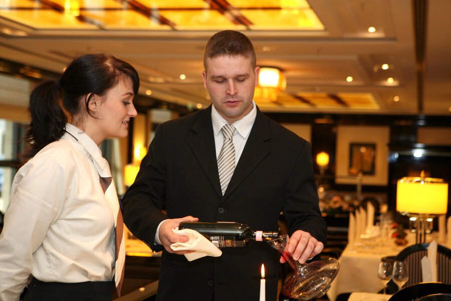 Junge Frau beobachtet in ihrer Ausbildung zur Fachkraft der Gastronomie den Ausbilder