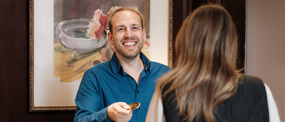 Mann an der Rezeption übergibt Gast einen Schlüssel