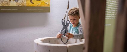 Junge probiert sich in der Ausstellung des Burgmuseums Querfurt an dem Anheben von Quadern mittels Steinzange