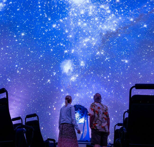 2 Menschen schauen sich die Sternenprojektion im Zeiss-Planetarium Jena an.