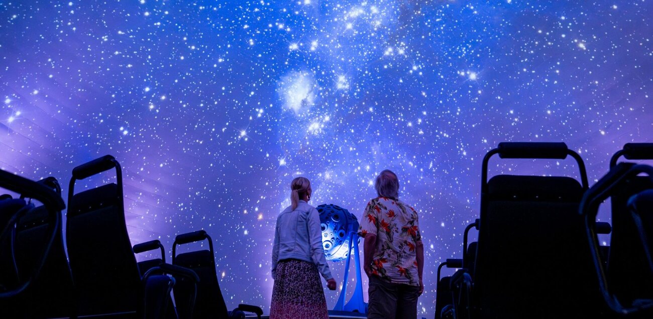 2 Menschen schauen sich die Sternenprojektion im Zeiss-Planetarium Jena an.