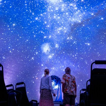 2 Menschen schauen sich die Sternenprojektion im Zeiss-Planetarium Jena an.