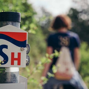 Wandernde Frau auf der SaaleHorizontale mit Wegweiser