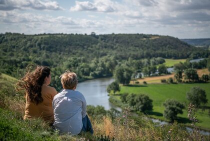 Zwei Frauen sitzen nebeneinander auf einem Hügel mit Blick auf den Saaledurchbruch Rothenburg