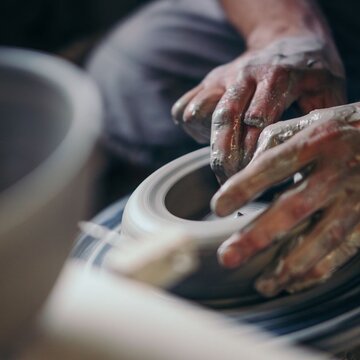 Hände formen mit Ton eine Vase auf einer Tonscheibe