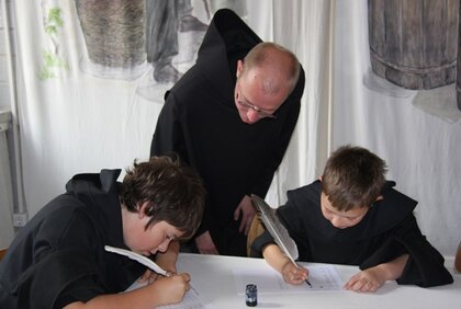 Benediktiner-Mönch unterrichtet zwei Kinder im Skriptorium des Klosters Memleben