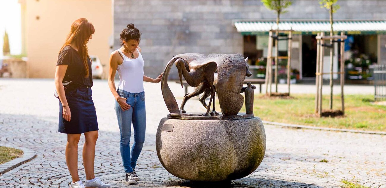 Zwei Frauen betrachten die Skulptur von Fuchs und Storch in der Altstadt von Hohenmölsen.
