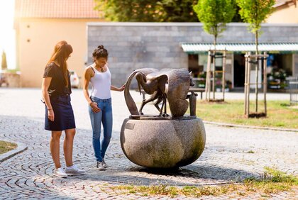 Zwei Frauen betrachten die Skulptur von Fuchs und Storch in der Altstadt von Hohenmölsen.