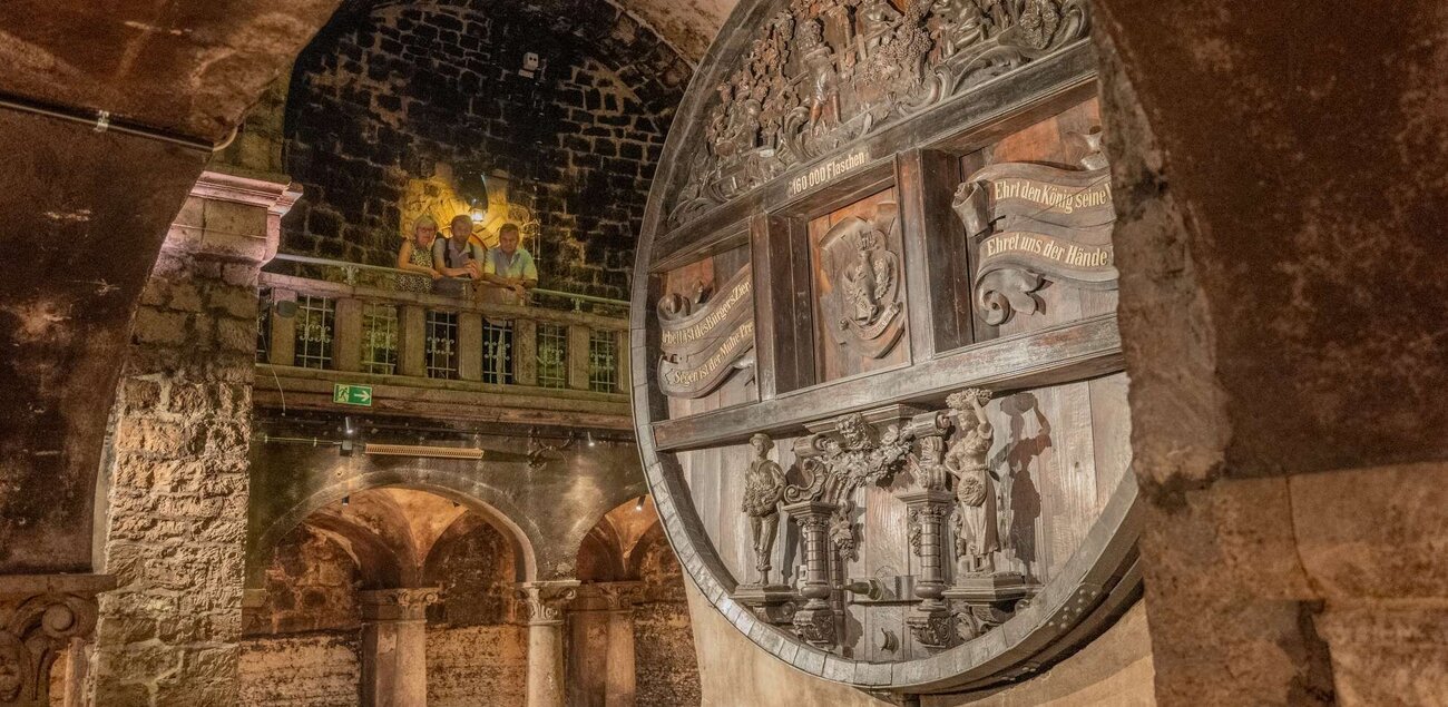 Keller der Rotkäppchen Sektkellerei mit dem größten Cuveefass Deutschlands, auf der oberen Empore stehen drei Personen