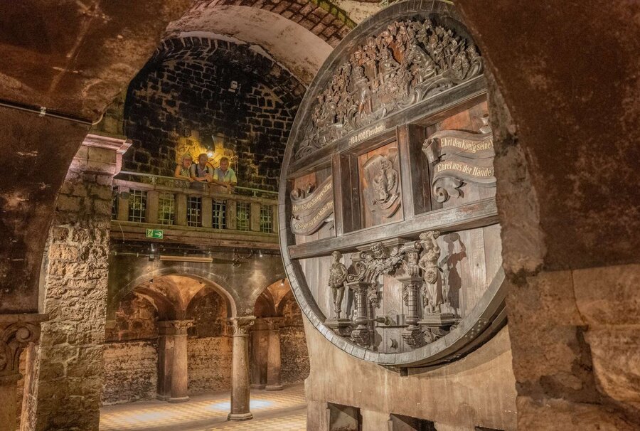 Keller der Rotkäppchen Sektkellerei mit dem größten Cuveefass Deutschlands, auf der oberen Empore stehen drei Personen