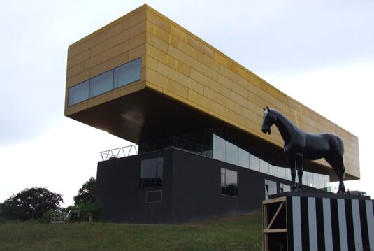 Ansicht der Arche Nebra davor steht eine schwarze Pferdefigur auf einem gestreiften Podest. (Kulisse für den Film "Bibi & Tina")