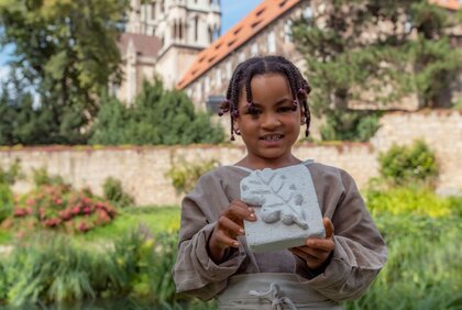 Junge zeigt sein in Stein gehauenes Blatt beim Kinderprojekt "Botanik in Stein" in der KinderDomBauhütte am Naumburger Dom