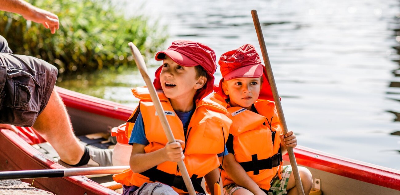 Zwei Kinder sitzen in einem Kanu auf dem Wasser.