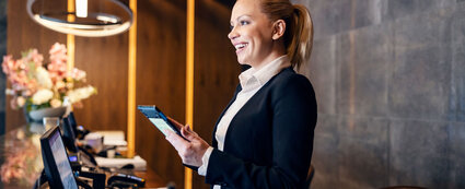 Junge Fachkraft an der Rezeption serviciert freundlich Gäste