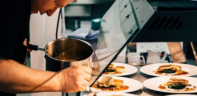 Koch beim anrichten von mehreren Speisen
