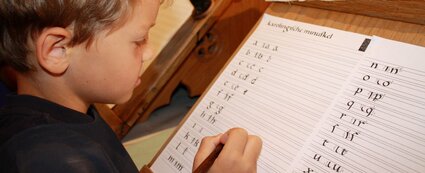 Kind versucht sich am Schreiben im Scriptorium des Kulturhistorischen Museums Schloss Merseburg