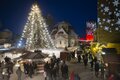 Veranstaltung Weihnachtszauber auf der Burg Querfurt, Marktstände und Menschen im Schnee, ein Weihnachtsbaum mit Lichterkette und auf die Burgmauern sind übergroße Schneeflocken projiziert