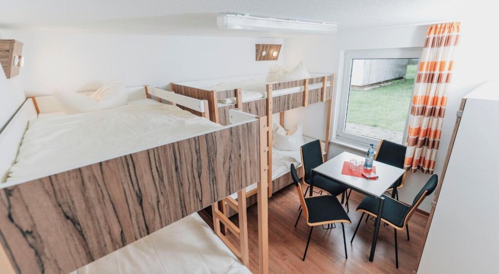 Zimmer der Jugendherberge Kretzschau mit Doppelstockbetten und Tisch mit Stühlen