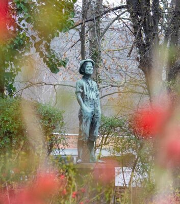 lustige Jungenfigur mit Hut im Stadtpark Weißenfels mit Frühlingsblüten