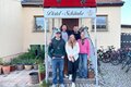 5 Personen stehen vor den Treppen der Distel-Schänke und blicken fröhlich in die Kamera.