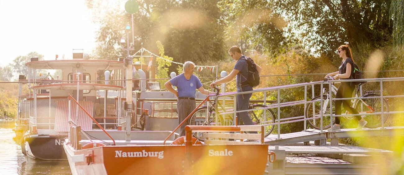 Radfahrer überqueren die Fähre im Blütengrund über die Saale