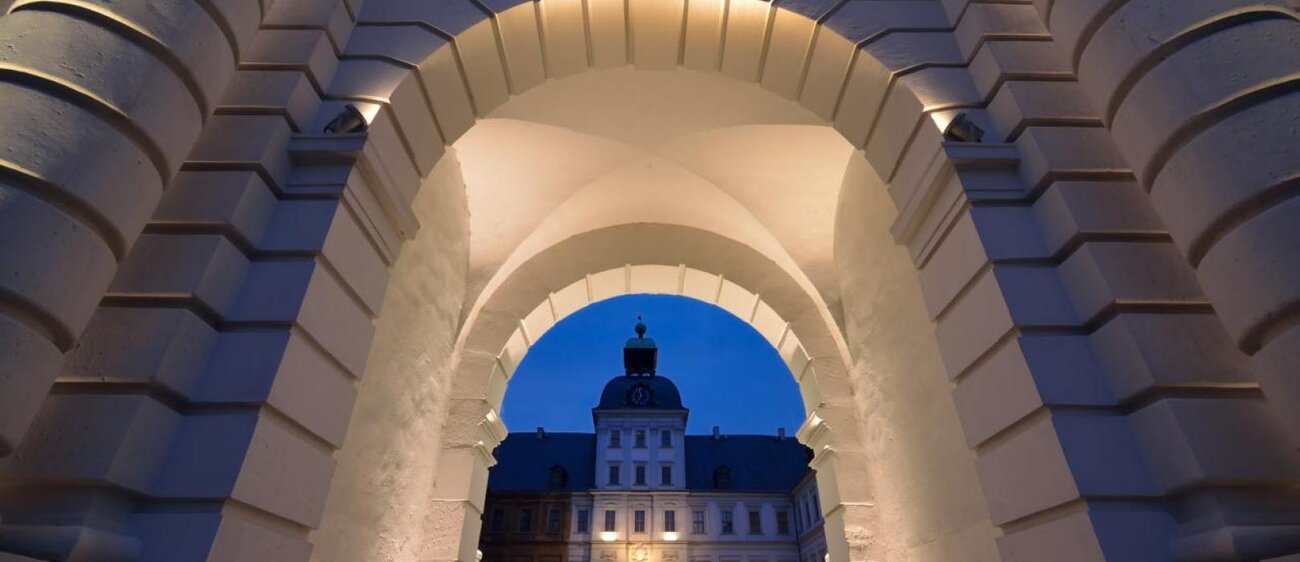 Blick auf Schloss Neu-Augustusburg Weißenfels durch den bei Nacht beleuchteten Torbogen