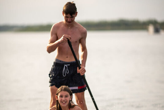 Zwei Jugendliche fahren mit einem Stand-up-Paddleboard auf dem Geiseltalsee