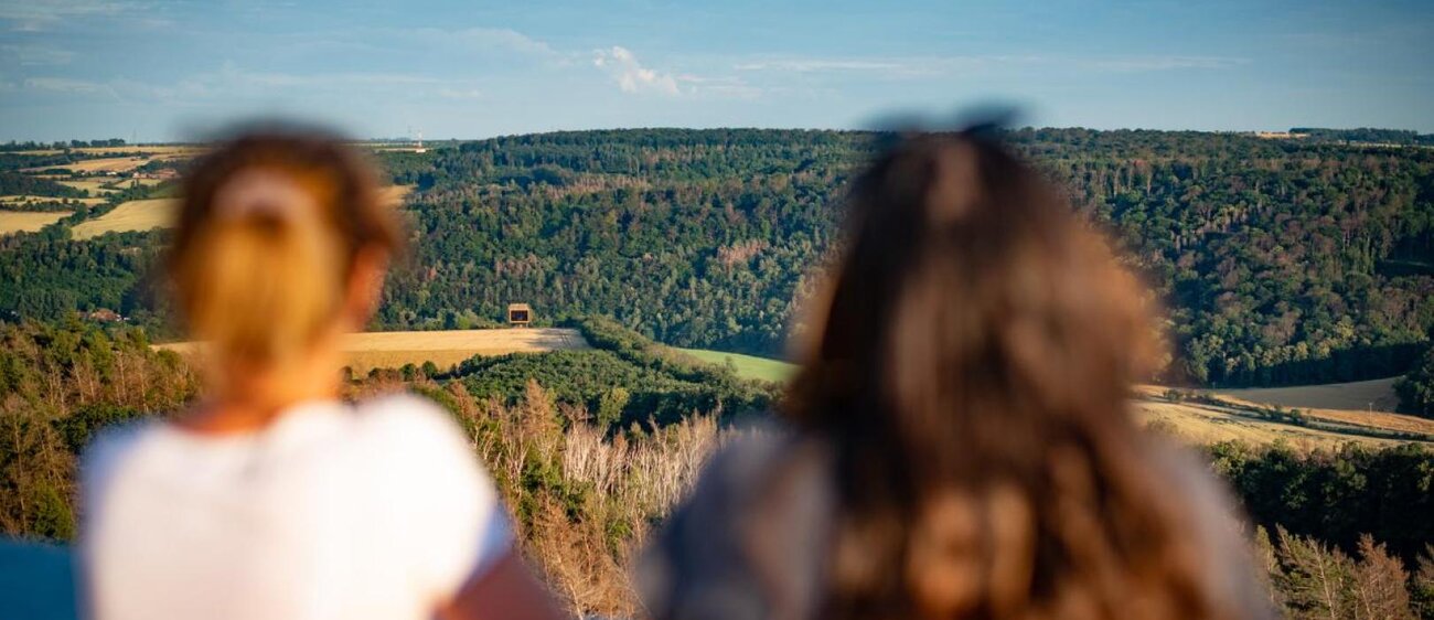 Zwei Frauen sind von hinten zu sehen, welche vom Mittelberg, dem Fundort der Himmelsscheibe, auf das Museum der Arche Nebra schauen.