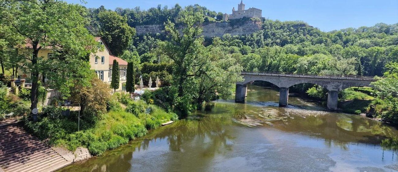 Außenansicht des Alten Fährhauses Saaleck mit Rudelsburg im Hintergrund