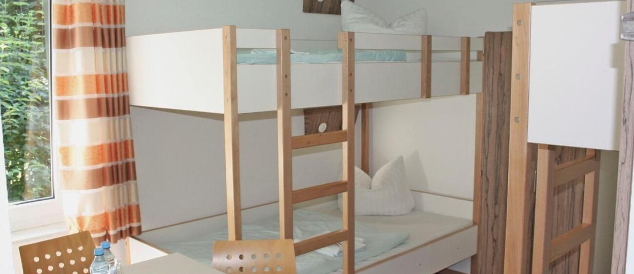 Zimmer der Jugendherberge Kretzschau mit Doppelstockbetten und Tisch mit Stühlen