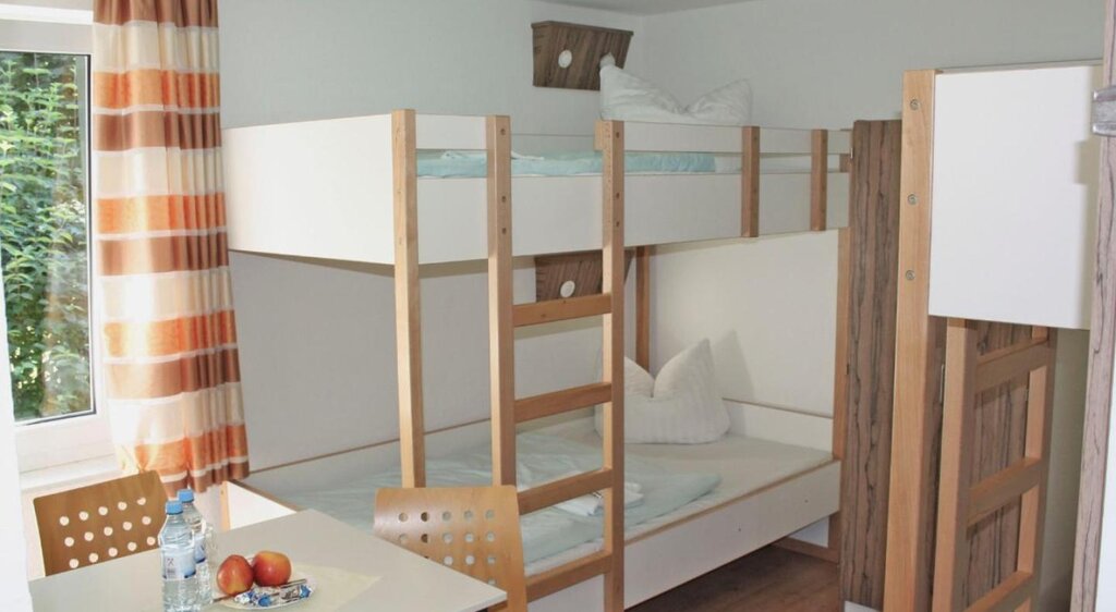 Zimmer der Jugendherberge Kretzschau mit Doppelstockbetten und Tisch mit Stühlen