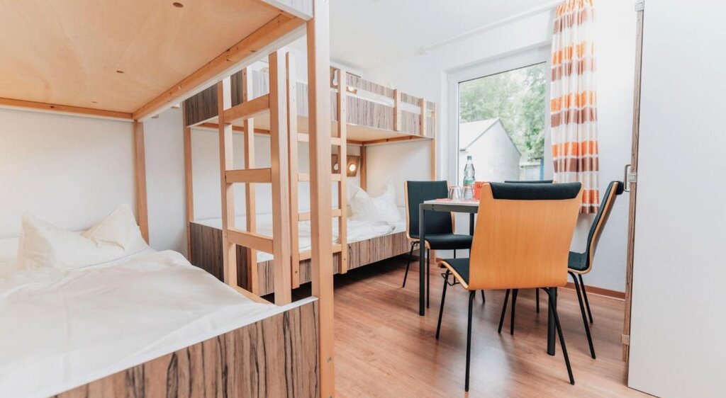 Zimmer der Jugendherberge Kretzschau mit Doppelstockbetten und Tisch mit Stühlen