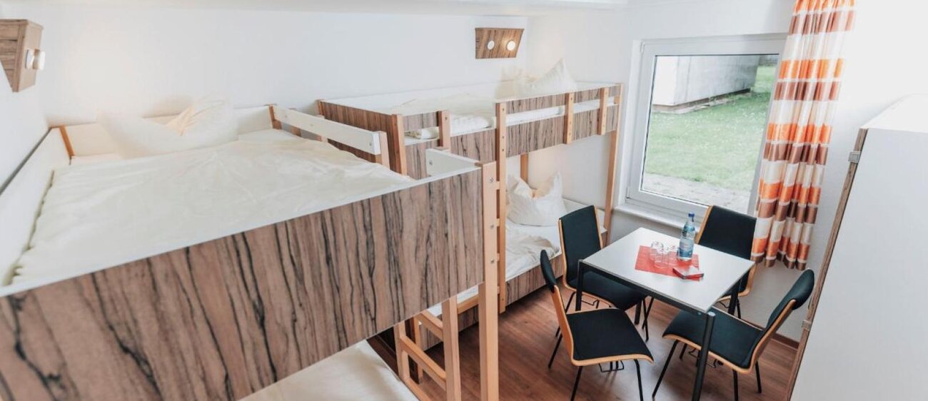 Zimmer der Jugendherberge Kretzschau mit Doppelstockbetten und Tisch mit Stühlen