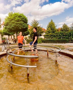 Zwei Personen die durch das Kneippbecken in Bad Bibra laufen.