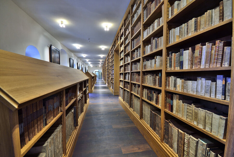 Domstiftsbibliothek im Naumburger Dom mit Holzregalen voller historischer Bücher auf beiden Seiten eines langen Ganges