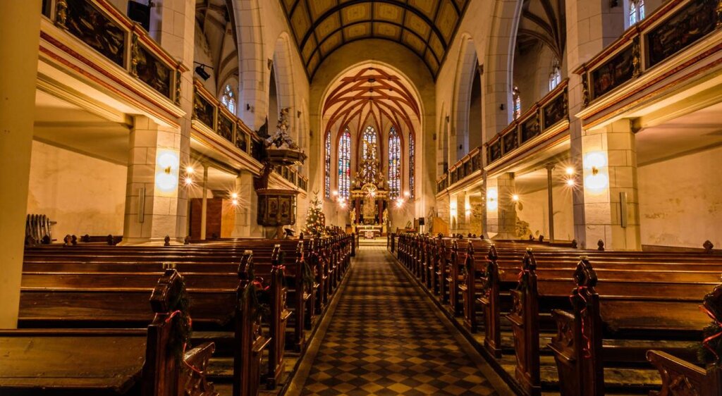 Innenraum der Stadtkirche St. Marien Weißenfels mit Emporen im Seitenschiff, Chorraum, Chorfenstern, Altar und Kanzel im Abendlicht
