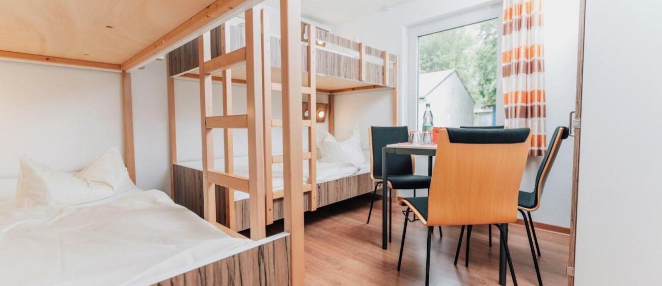 Zimmer der Jugendherberge Kretzschau mit Doppelstockbetten und Tisch mit Stühlen