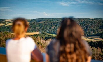 Zwei Frauen sind von hinten zu sehen, welche vom Mittelberg, dem Fundort der Himmelsscheibe, auf das Museum der Arche Nebra schauen.